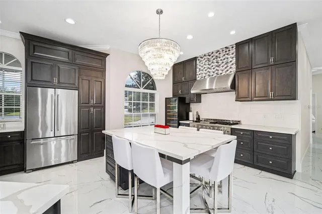 a kitchen with stainless steel appliances granite countertop a refrigerator a sink dishwasher a stove a dining table and chairs with wooden floor