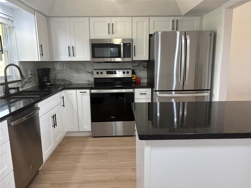 4725 Cove Circle, Unit 405 St. Petersburg, FL 33708 - Photo 4 of 23 a kitchen with stainless steel appliances a refrigerator sink and microwave