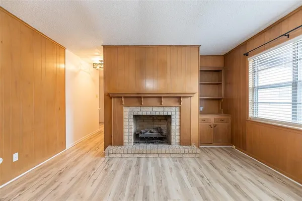 an empty room with windows fireplace and wooden floor