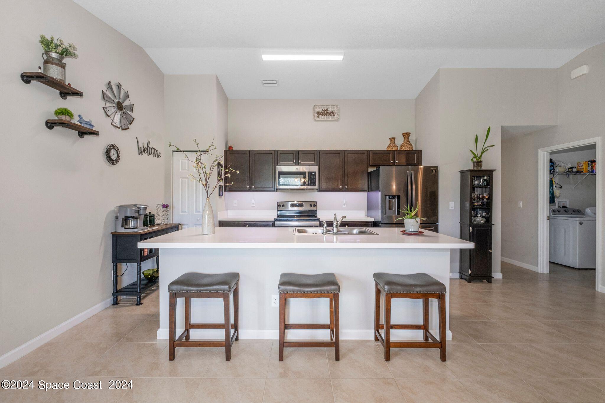 1011 Grapefruit Road Southeast Palm Bay, FL 32909 - Photo 11 of 42 a kitchen with cabinets a sink and chairs