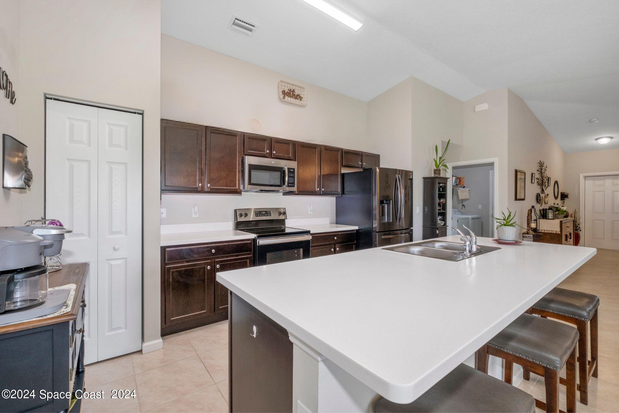 1011 Grapefruit Road Southeast Palm Bay, FL 32909 - Photo 12 of 42 a kitchen with kitchen island a sink stove and refrigerator