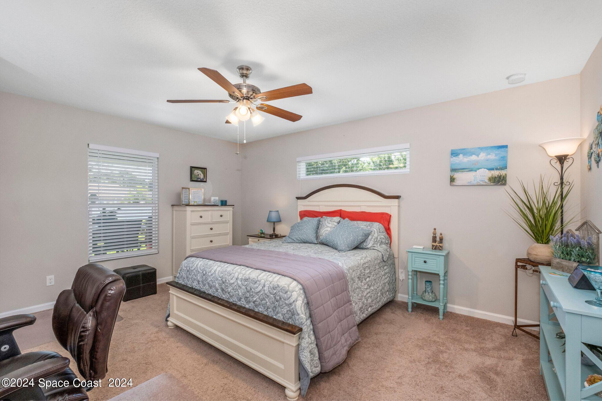 1011 Grapefruit Road Southeast Palm Bay, FL 32909 - Photo 15 of 42 a bedroom with a bed a couch and potted plant on the dresser