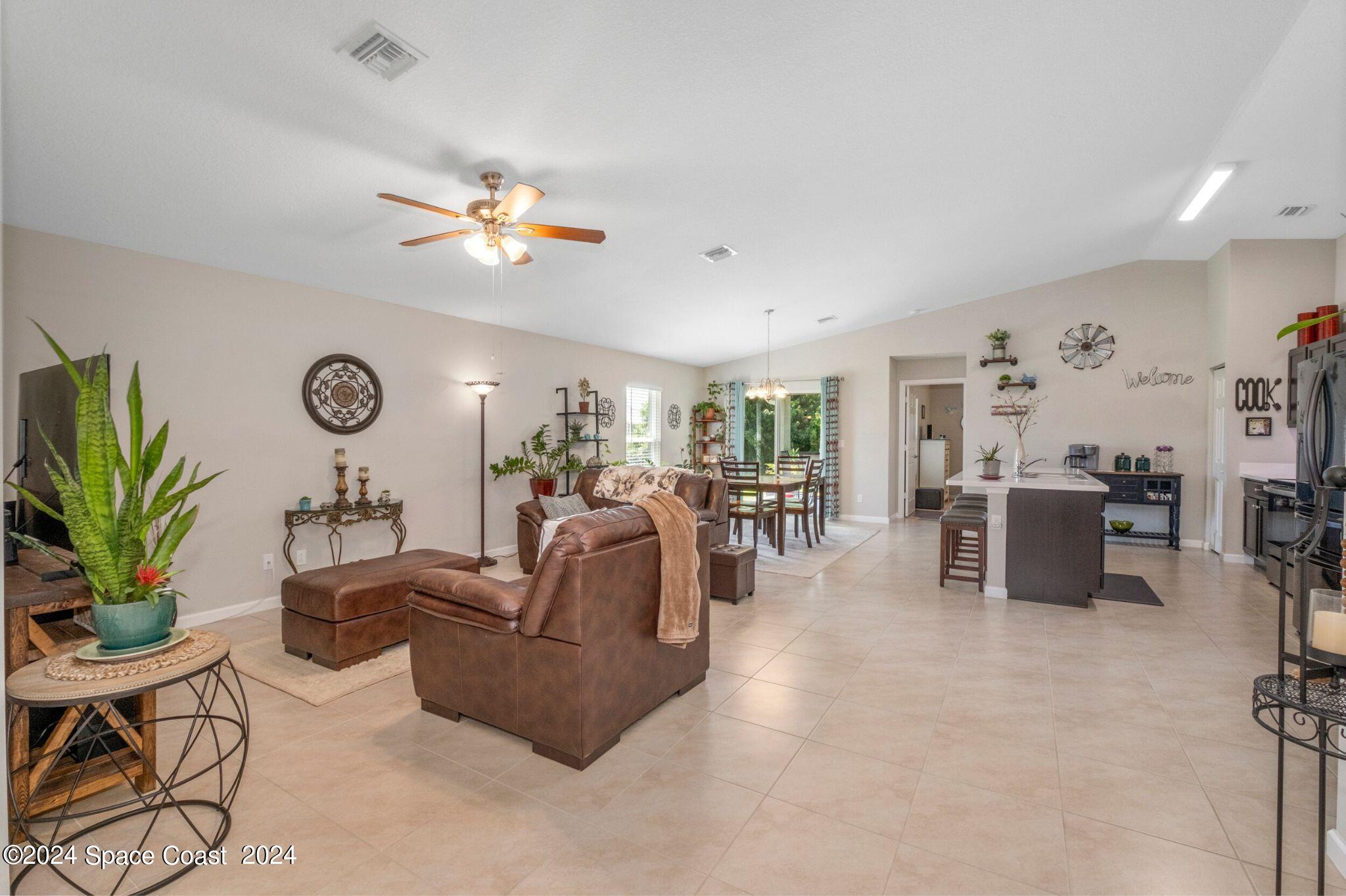 1011 Grapefruit Road Southeast Palm Bay, FL 32909 - Photo 5 of 42 a living room with furniture a chandelier fan and a window