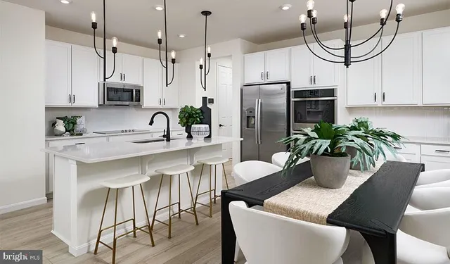 a kitchen with stainless steel appliances granite countertop a dining table chairs and white cabinets