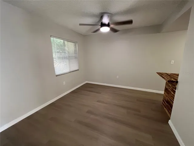 an empty room with wooden floor fan and windows