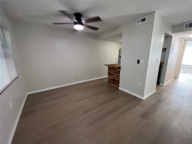 an empty room with wooden floor and fan