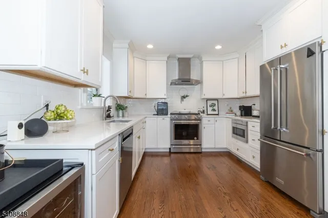 a kitchen with kitchen island white cabinets stainless steel appliances and wooden floor