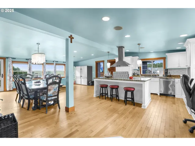 a kitchen with stainless steel appliances kitchen island granite countertop a table chairs and a refrigerator