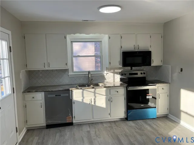 a kitchen with stainless steel appliances a stove top oven a sink a counter space and cabinets