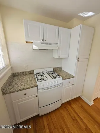 a kitchen with granite countertop white cabinets and white appliances