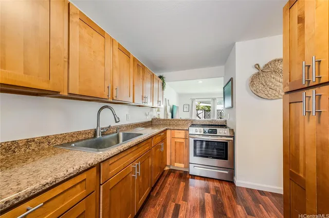 a kitchen with granite countertop stainless steel appliances a stove a sink and a refrigerator with wooden floor