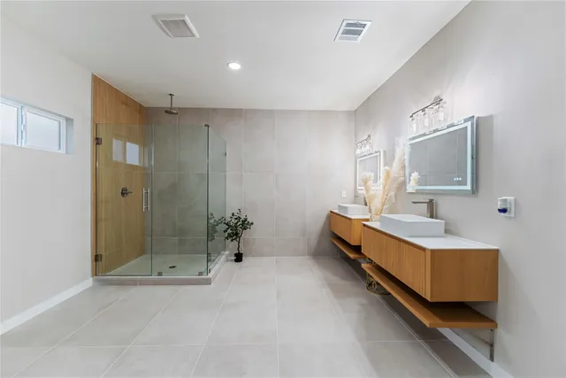 a bathroom with a double vanity sink a large mirror and shower
