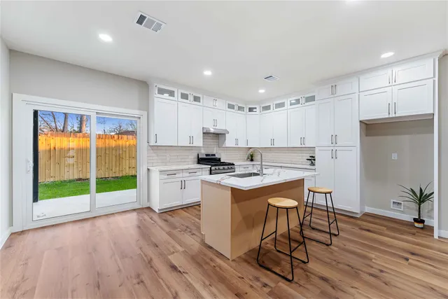 a kitchen that has a lot of cabinets and wooden floor
