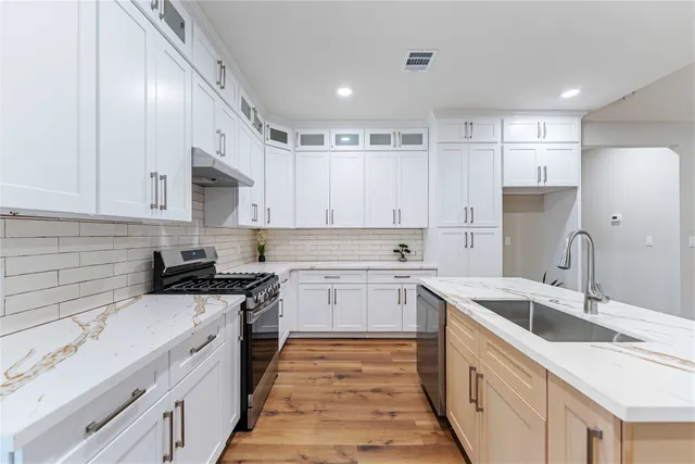 a kitchen with granite countertop a sink and white cabinets