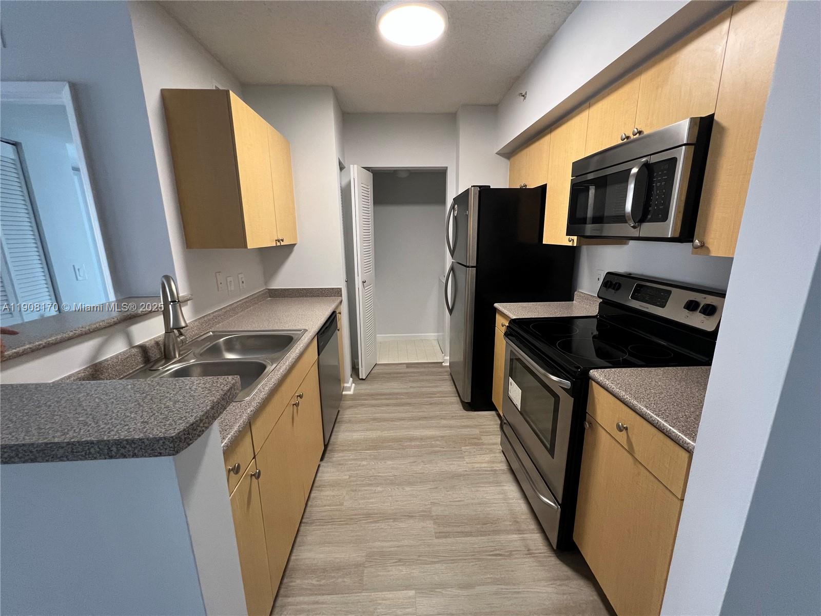 1919 Van Buren Street, Unit 720A Hollywood, FL 33020 - Photo 5 of 22 a kitchen with stainless steel appliances granite countertop a stove a sink and a refrigerator