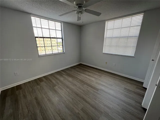 an empty room with wooden floor chandelier and windows