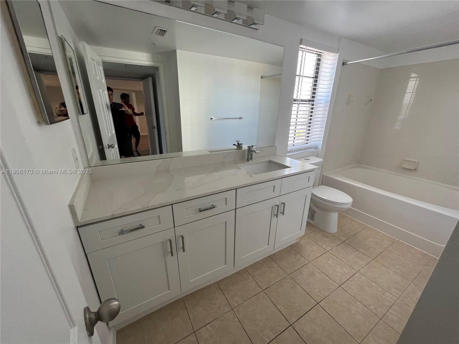 1919 Van Buren Street, Unit 720A Hollywood, FL 33020 - Photo 10 of 22 a bathroom with a granite countertop sink a toilet a mirror a bathtub and window