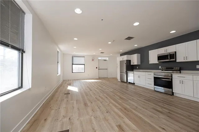 a view of kitchen with microwave a stove and wooden floor