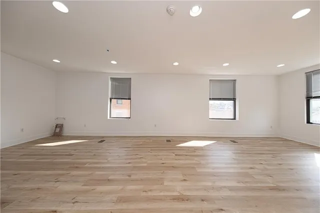 a view of an empty room with window and wooden floor