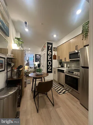 a kitchen with stainless steel appliances kitchen island granite countertop a refrigerator a stove a sink dishwasher and a dining table with wooden floor