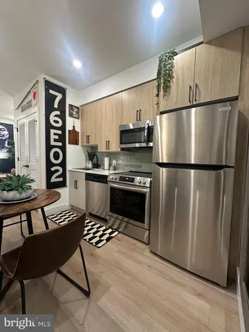 a kitchen with stainless steel appliances a refrigerator a stove a sink a dining table and chairs