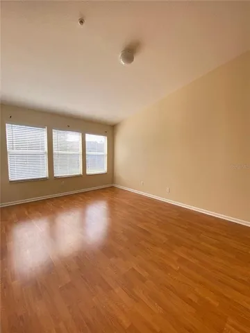 a view of empty room with wooden floor and fan