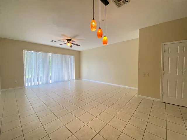 an empty room with windows and ceiling fan