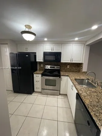 a kitchen with granite countertop a refrigerator and a stove top oven