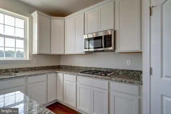 a kitchen with stainless steel appliances granite countertop white cabinets sink and window