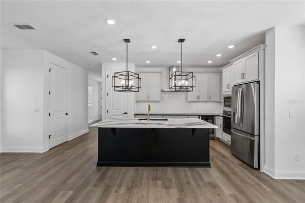 a kitchen with stainless steel appliances granite countertop a sink a stove and a refrigerator