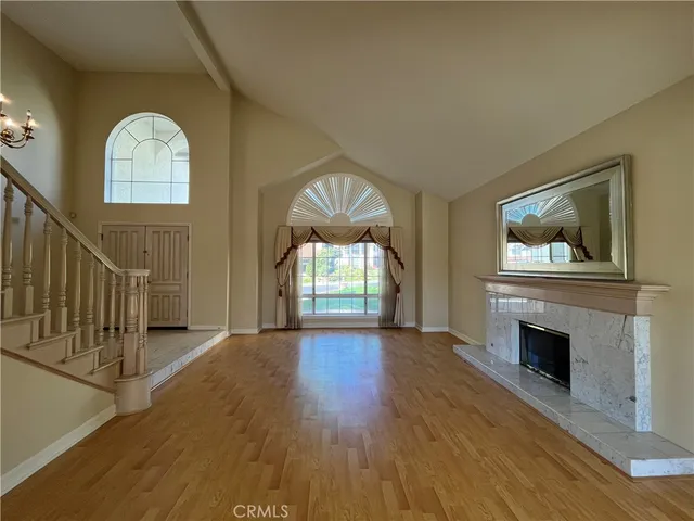 an empty room with wooden floor fireplace and windows