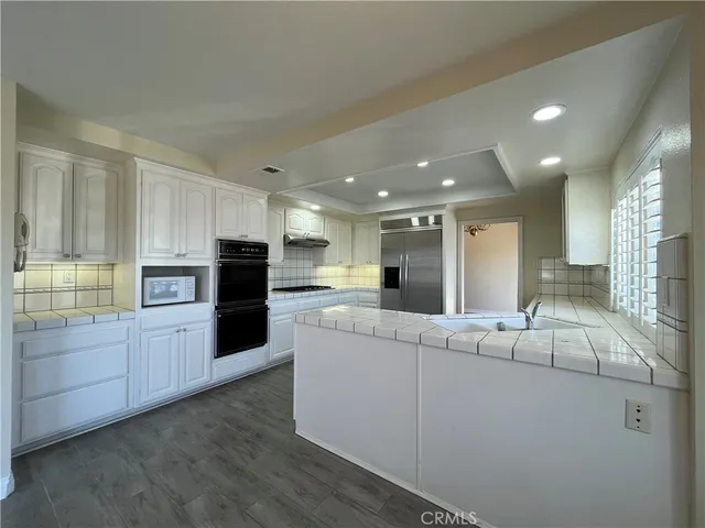 a kitchen with stainless steel appliances kitchen island granite countertop a refrigerator and a sink