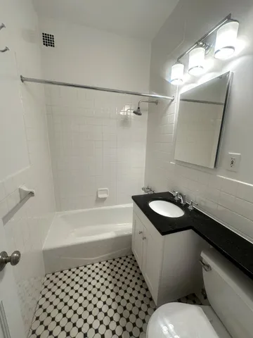 a bathroom with a granite countertop sink a toilet a mirror and shower