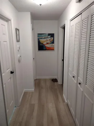 a view of a hallway with wooden floor and a bathroom