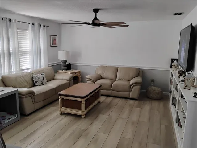 a living room with furniture a flat screen tv and a window