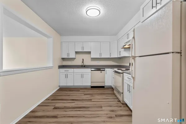 a kitchen with a refrigerator a stove top oven and white cabinets