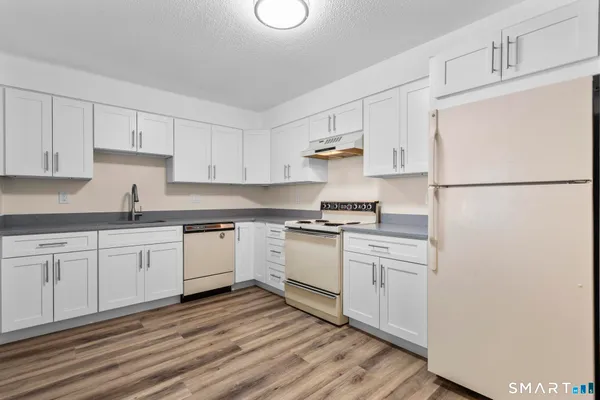 a kitchen with granite countertop white cabinets and white appliances