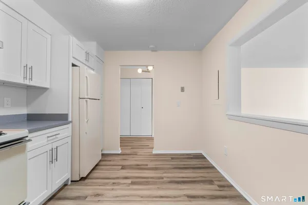 a view of a kitchen with white cabinets and wooden floor
