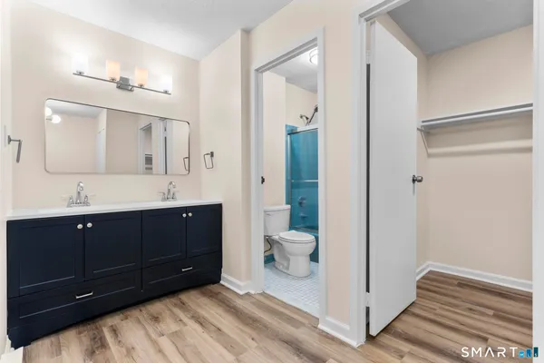 a spacious bathroom with a double vanity sink a toilet and a mirror