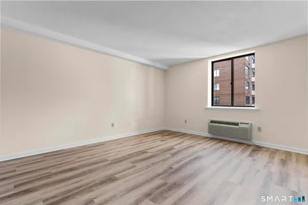 a view of an empty room with wooden floor and a window