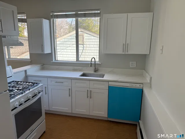 a kitchen with granite countertop a sink cabinets stainless steel appliances and a window