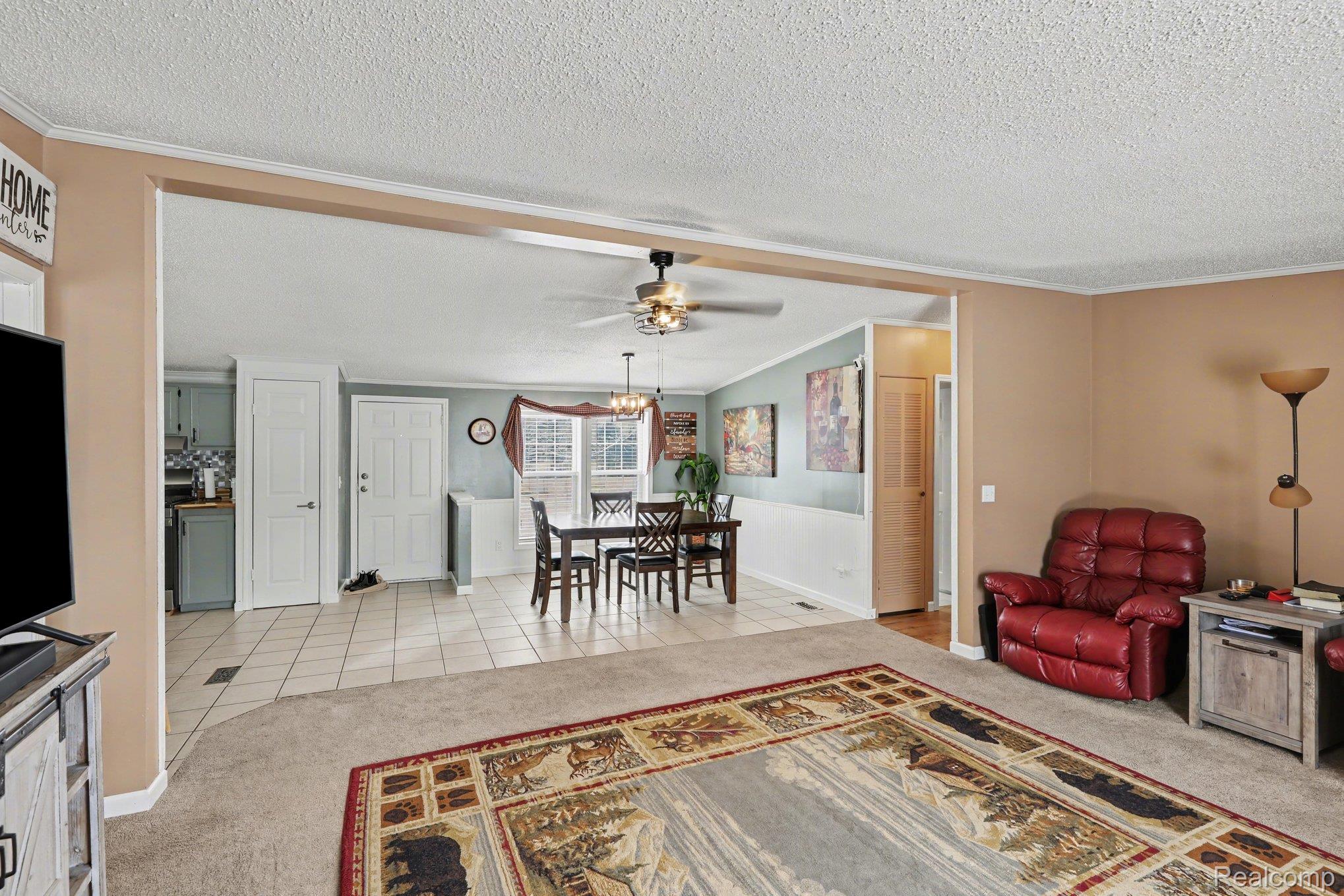 4458 Palms Road Casco, MI 48064 - Photo 9 of 32 Living room featuring light colored carpet, crown molding, ceiling fan, a textured ceiling, and light tile patterned floors