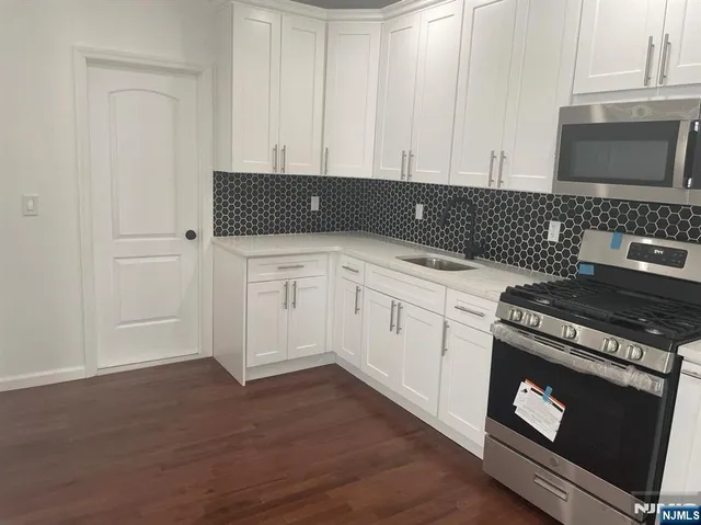 a view of kitchen with granite countertop white cabinets and black appliances
