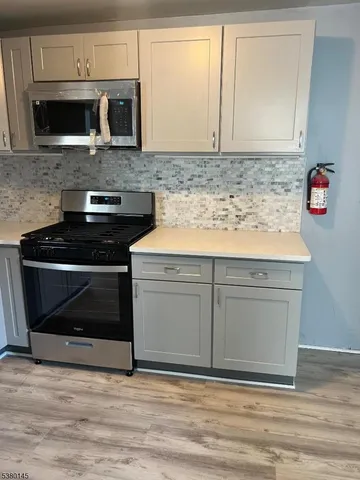 a kitchen with granite countertop cabinets stainless steel appliances and wooden floor