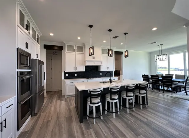 a large kitchen with a table and stainless steel appliances