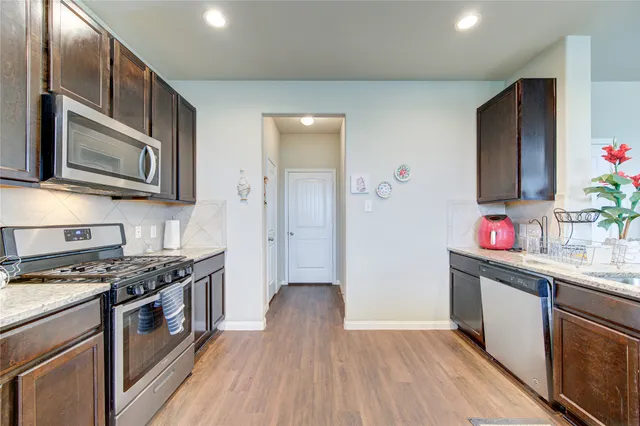 a kitchen with stainless steel appliances kitchen island granite countertop a stove a sink dishwasher and a microwave oven with wooden floor