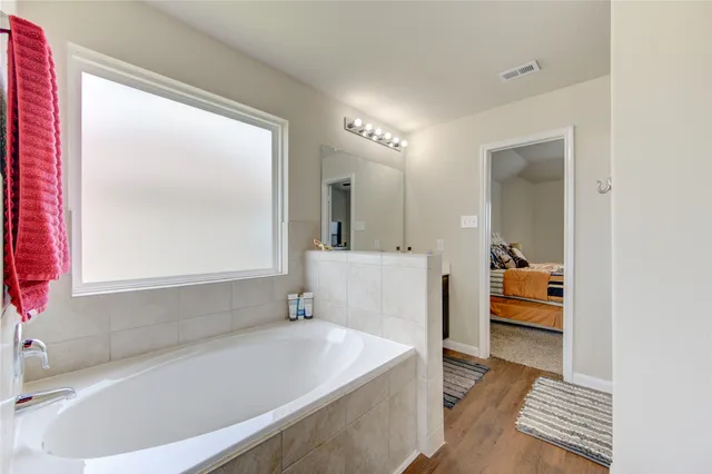 a bathroom with a tub a sink and a large mirror