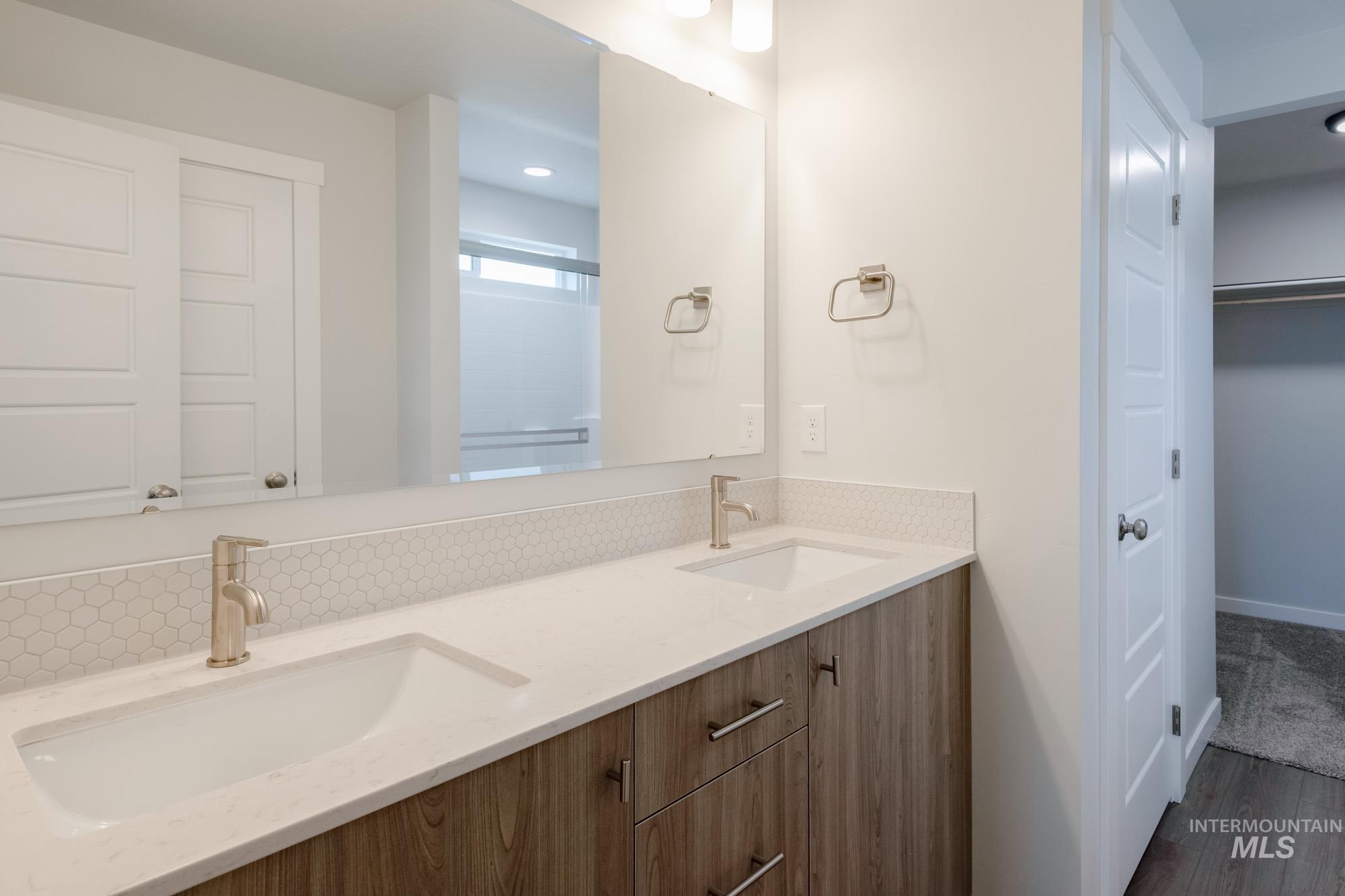 10575 West Teratai Street Star, ID 83669 - Photo 24 of 26 Bathroom with double vanity, a shower stall, a spacious closet, and dark wood-style floors