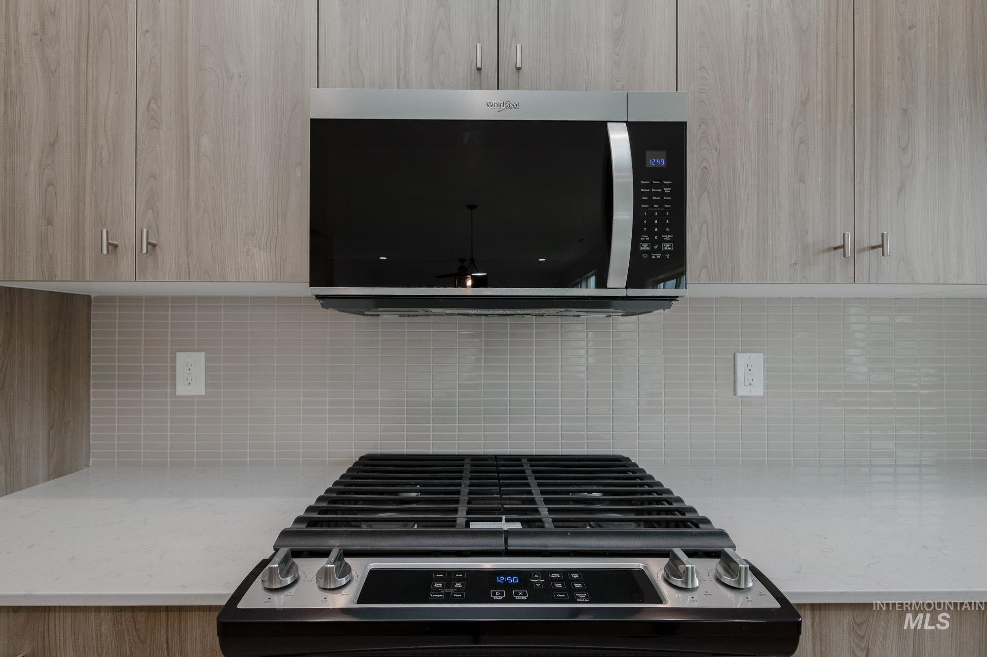 10575 West Teratai Street Star, ID 83669 - Photo 7 of 26 Kitchen with stainless steel microwave, light stone countertops, range with gas stovetop, and modern cabinets