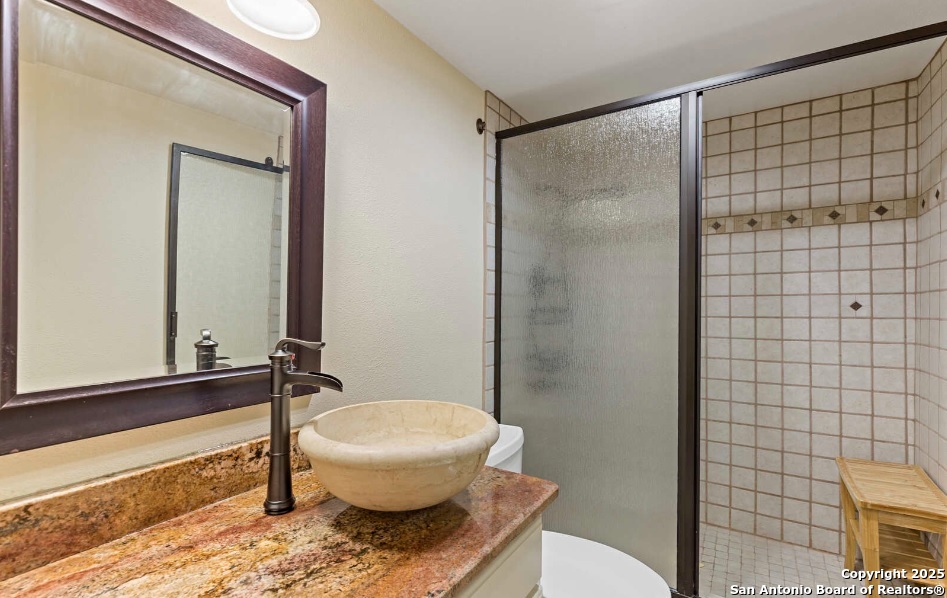 7701 Wurzbach Road, Unit 1205 San Antonio, TX 78229 - Photo 27 of 38 a bathroom with a granite countertop bathtub shower sink and toilet